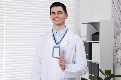 Photo of Smiling doctor showing empty badge in hospital