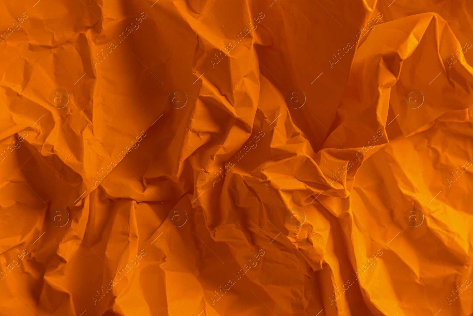 Photo of Texture of orange crumpled paper as background, top view