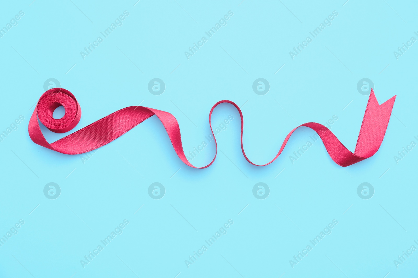 Photo of Simple pink ribbon on color background, top view