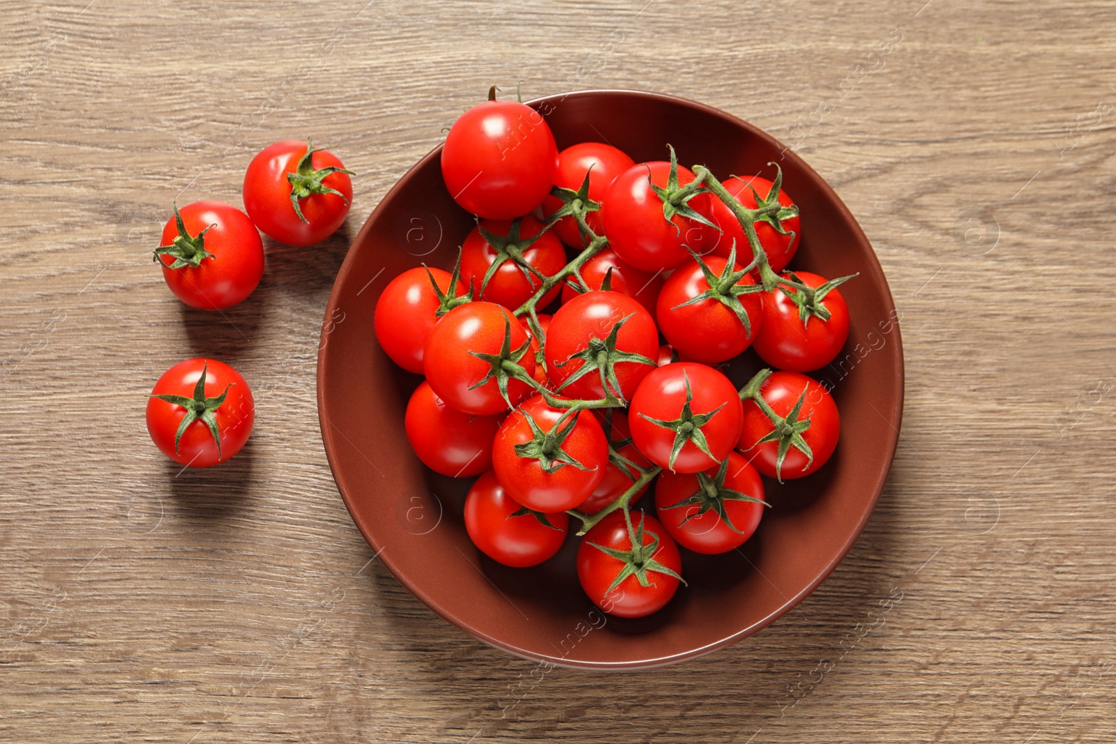 Photo of Plate with fresh cherry tomatoes on wooden background, top view