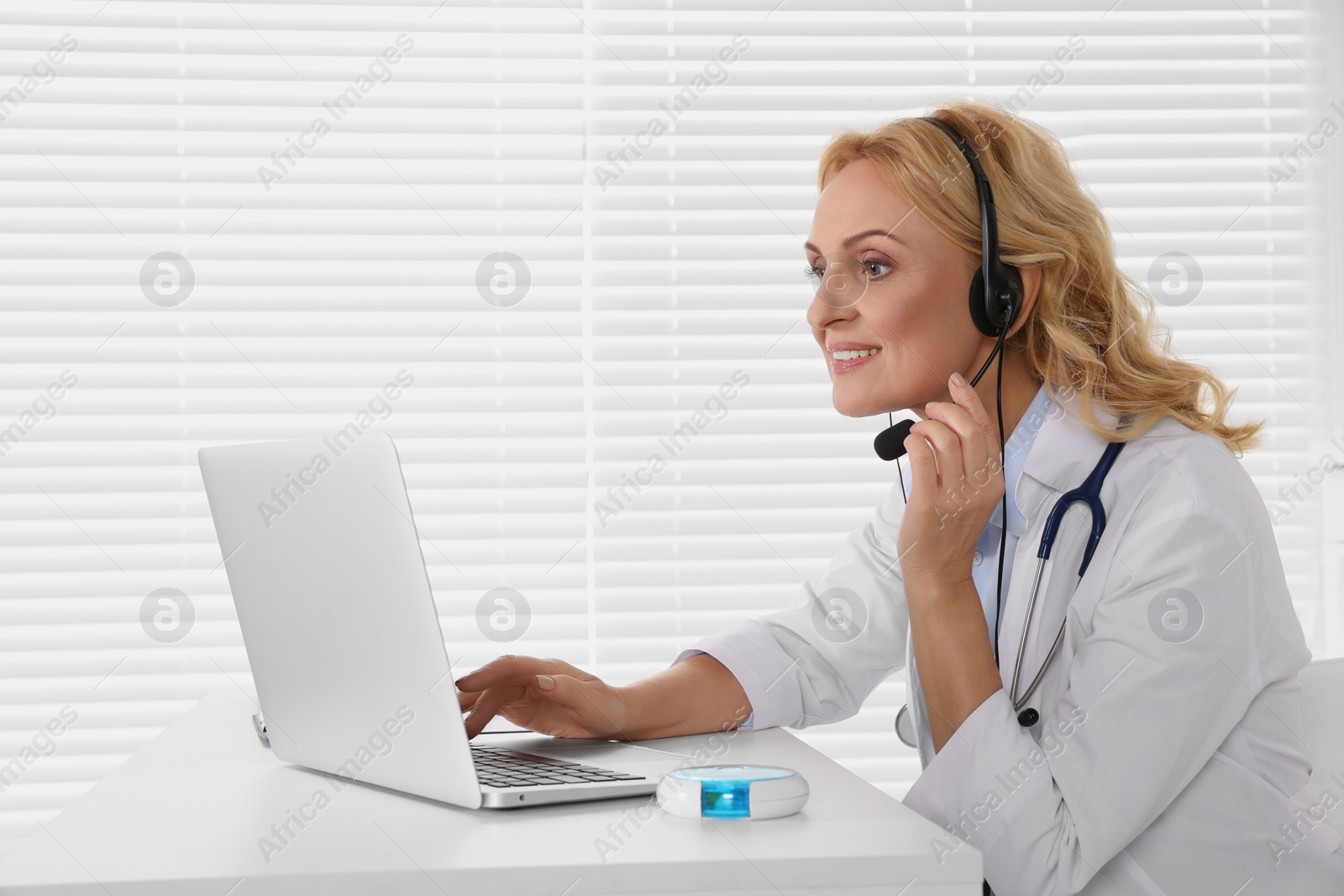 Photo of Doctor with laptop and headphones consulting patient in clinic. Online medicine concept