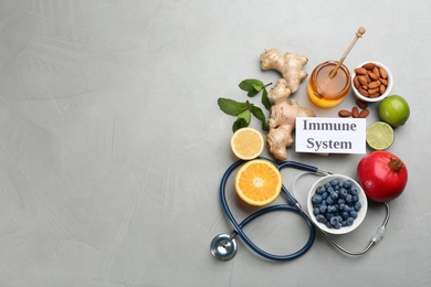 Photo of Set of natural products, stethoscope and card with text Immune System on grey table, flat lay