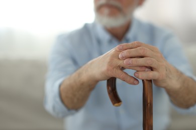 Photo of Grandpa with wooden walking cane indoors, closeup