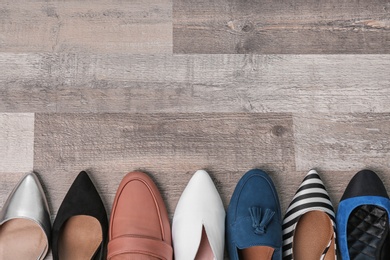 Different female shoes on wooden background, top view