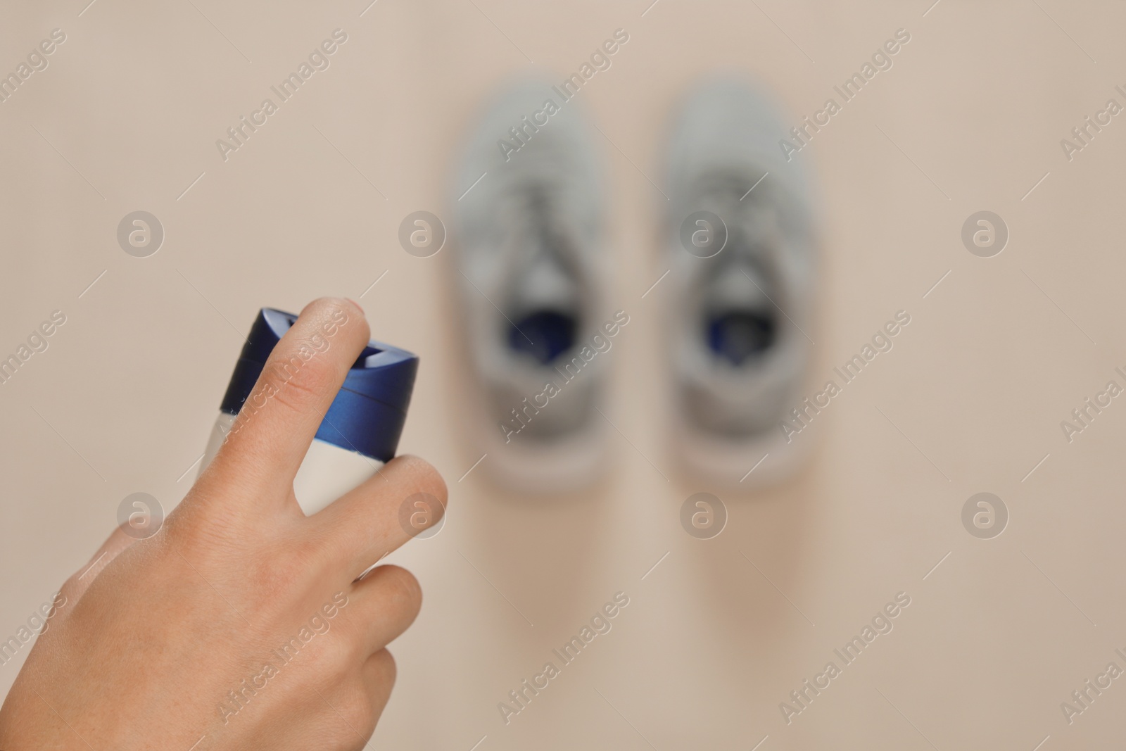 Photo of Woman spraying deodorant over pair of shoes at home, closeup. Space for text