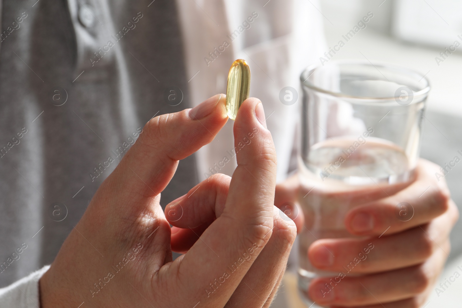 Photo of Man with glass of water and pill on blurred background, closeup