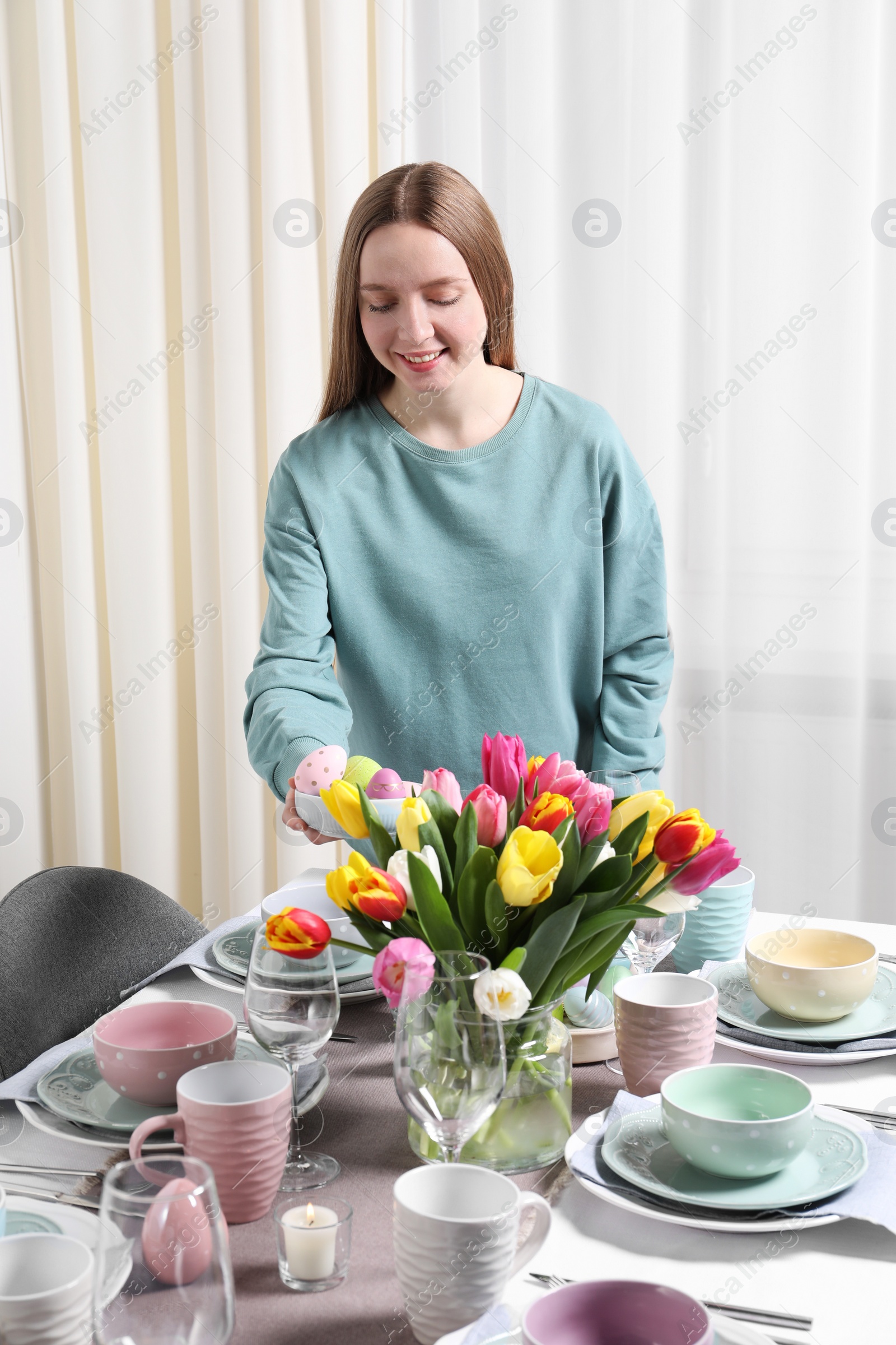 Photo of Woman setting table for festive Easter dinner at home