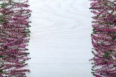 Photo of Heather branches with beautiful flowers on white wooden table, flat lay. Space for text