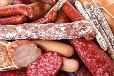 Different tasty sausages as background, closeup view