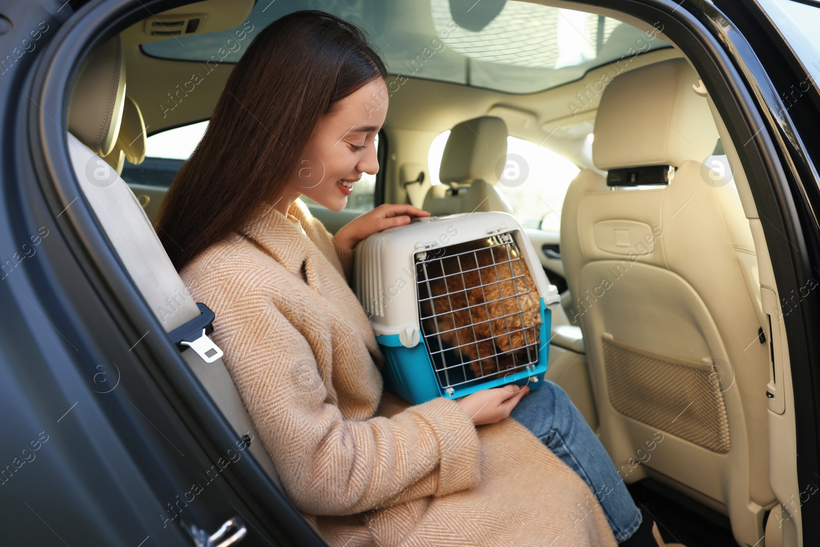 Photo of Smiling woman with pet carrier travelling with her dog by car