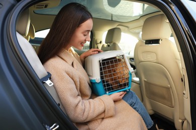 Smiling woman with pet carrier travelling with her dog by car