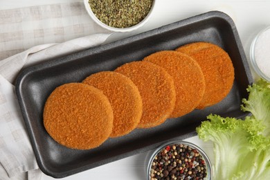 Uncooked breaded cutlets on white wooden table, flat lay. Freshly frozen semi-finished product