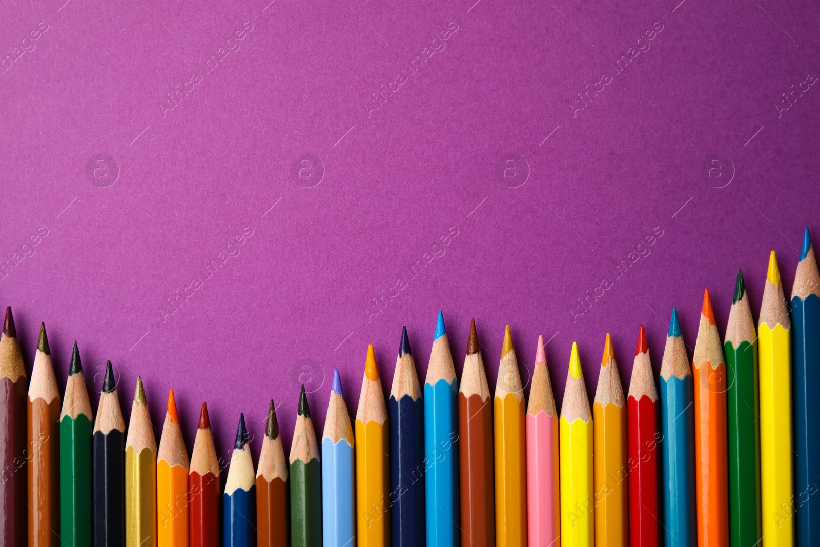 Photo of Flat lay composition with color pencils on purple background. Space for text