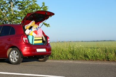 Family car with open trunk full of luggage on highway. Space for text