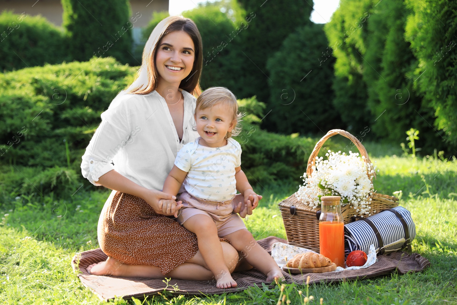 Photo of Mother with her baby daughter having picnic in garden on sunny day