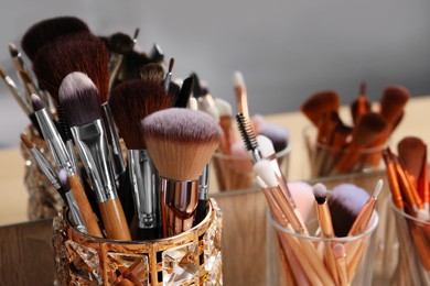 Photo of Set of professional makeup brushes near mirror on wooden table, closeup