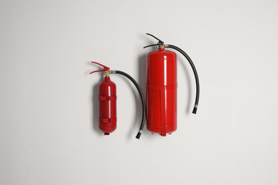 Photo of Different fire extinguishers hanging on white wall
