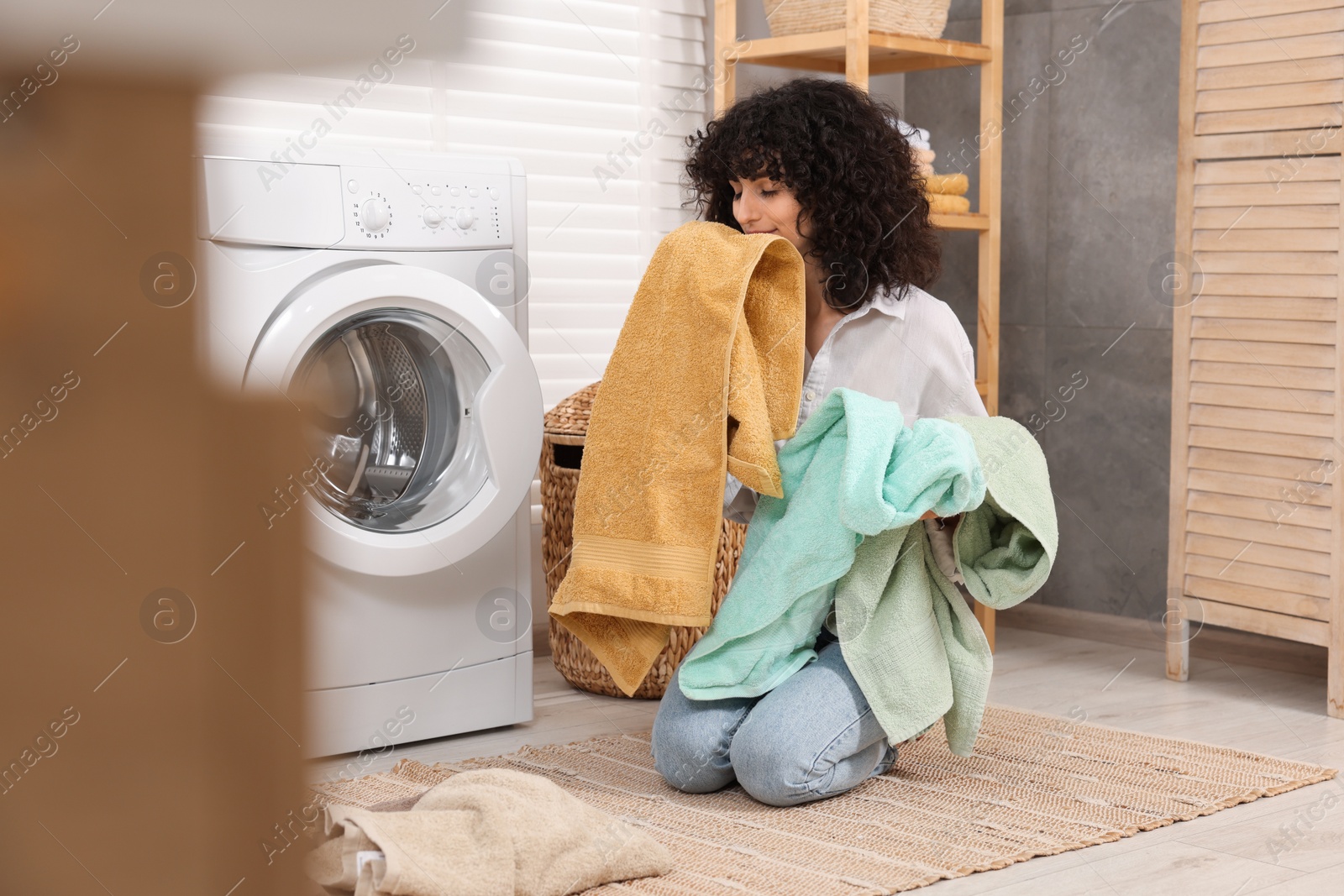 Photo of Woman with laundry near washing machine indoors