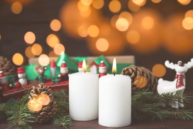 Photo of Burning candles and festive decor on wooden table, bokeh effect. Christmas eve