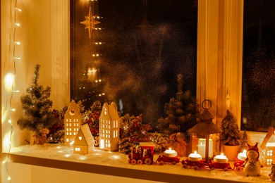 House shaped lanterns and Christmas decor on windowsill indoors