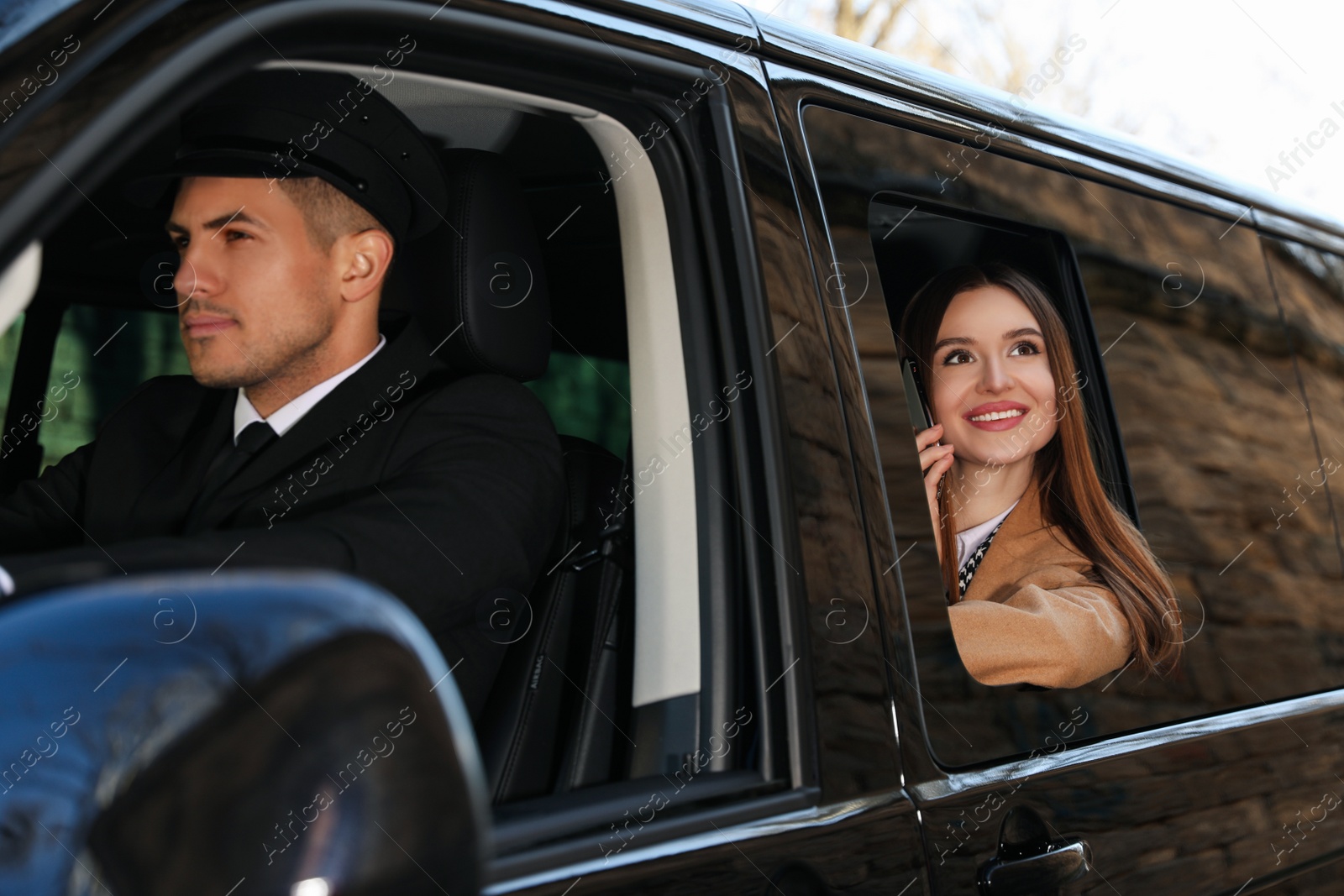 Photo of Professional driver and businesswoman in luxury car. Chauffeur service