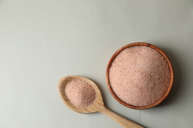 Photo of Himalayan salt in bowl and spoon on grey background, flat lay. Space for text