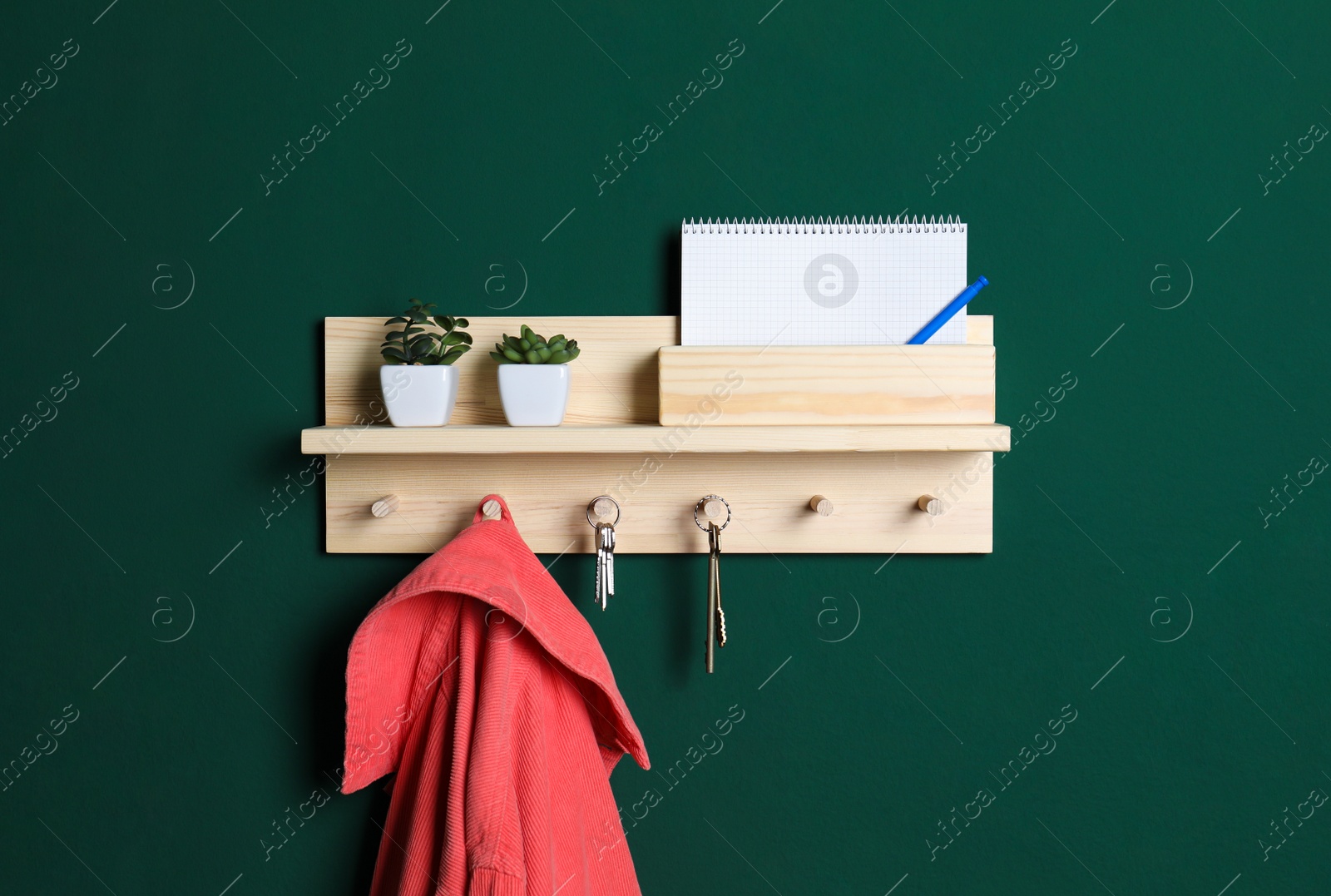 Photo of Wooden hanger for keys with clothes on green wall