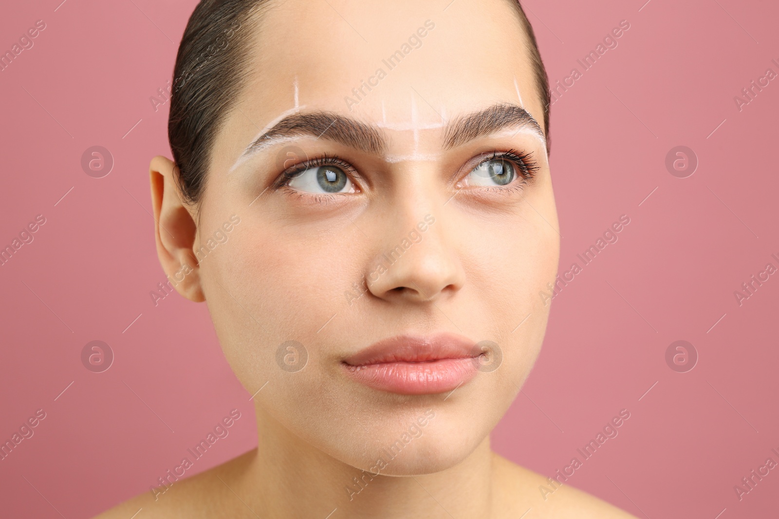 Photo of Eyebrow correction. Young woman with markings on face against pink background