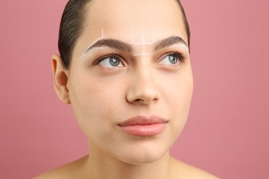 Photo of Eyebrow correction. Young woman with markings on face against pink background