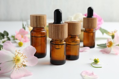 Photo of Aromatherapy. Essential oils and flowers on white table, closeup