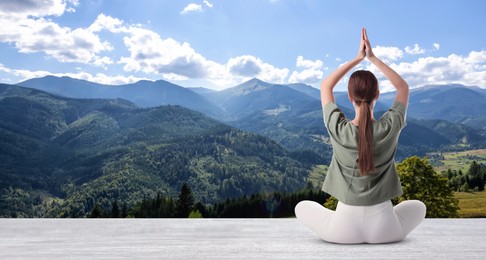 Young woman practicing yoga on white wooden surface against beautiful mountain landscape, space for text. Banner design