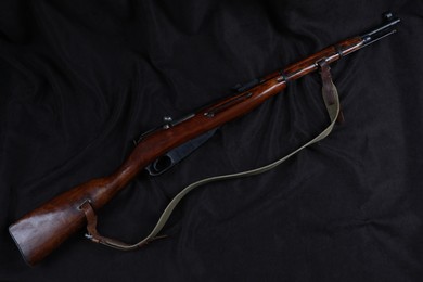 Photo of Vintage hunting gun on dark fabric, top view