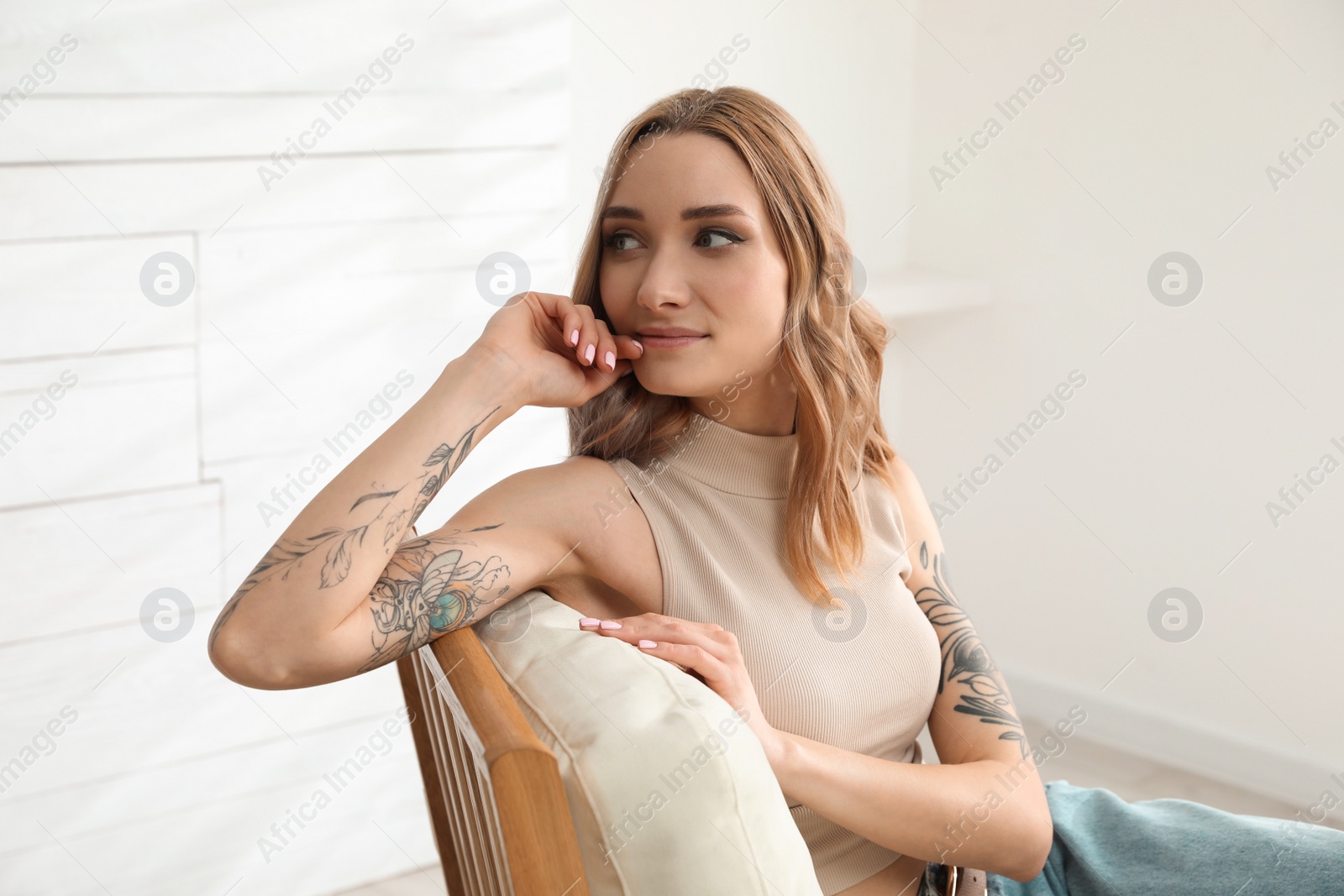 Photo of Beautiful woman with tattoos on arms resting at home