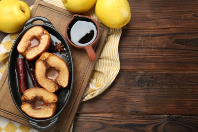 Tasty baked quinces served with sauce on wooden table, flat lay. Space for text