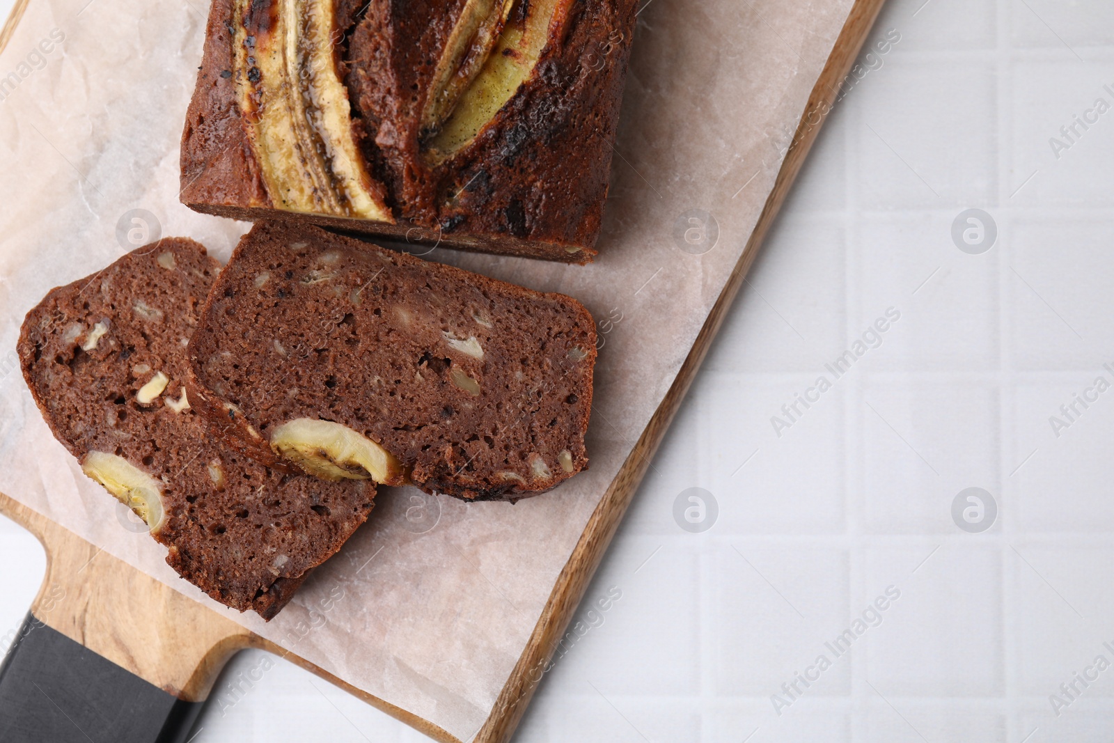 Photo of Delicious banana bread on white tiled table, top view