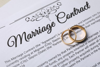 Marriage contract and gold rings on table, above view