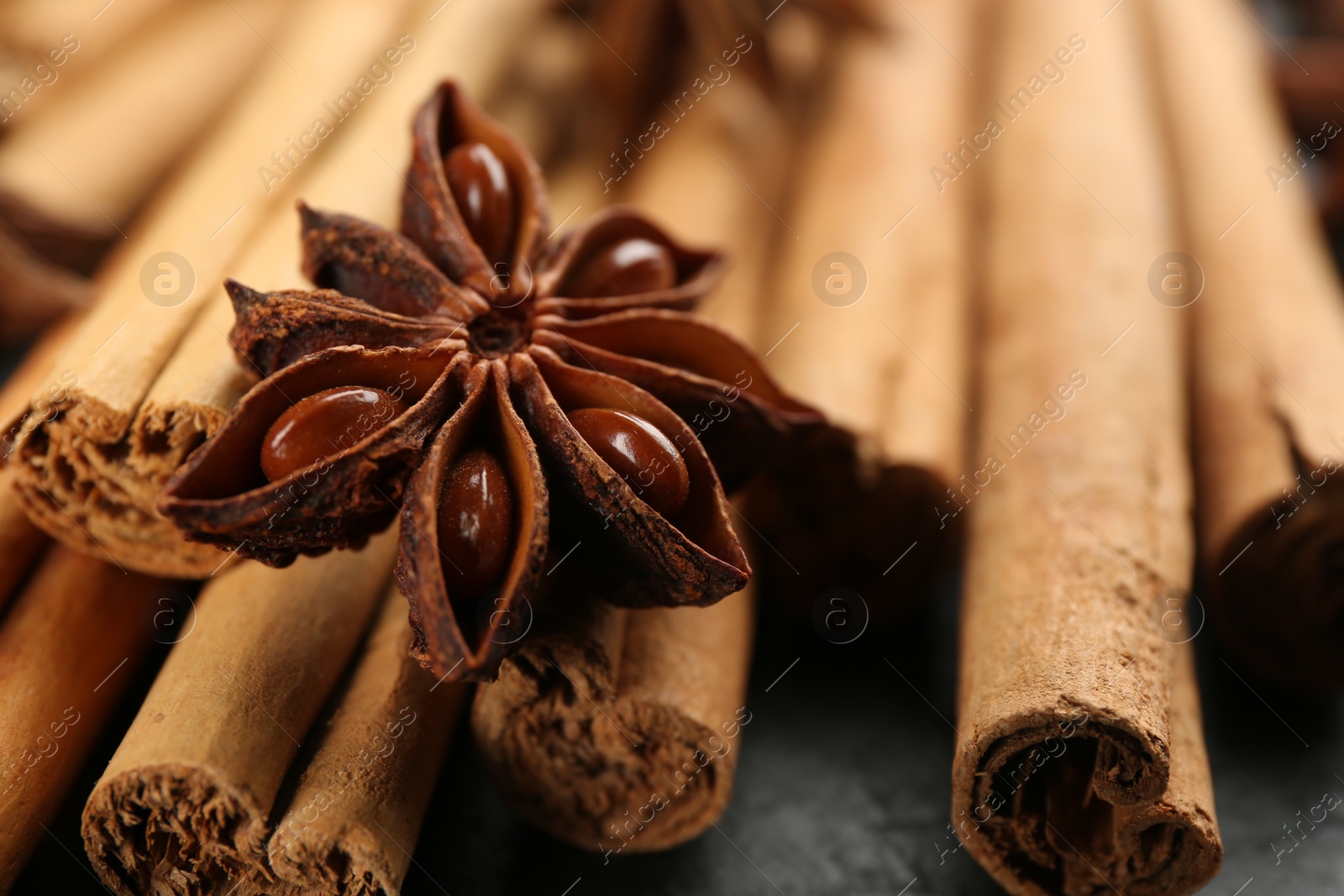 Photo of Aromatic cinnamon sticks and anise on table, closeup