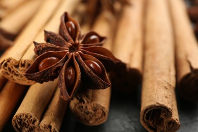 Photo of Aromatic cinnamon sticks and anise on table, closeup