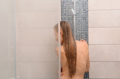 Beautiful young woman taking shower at home