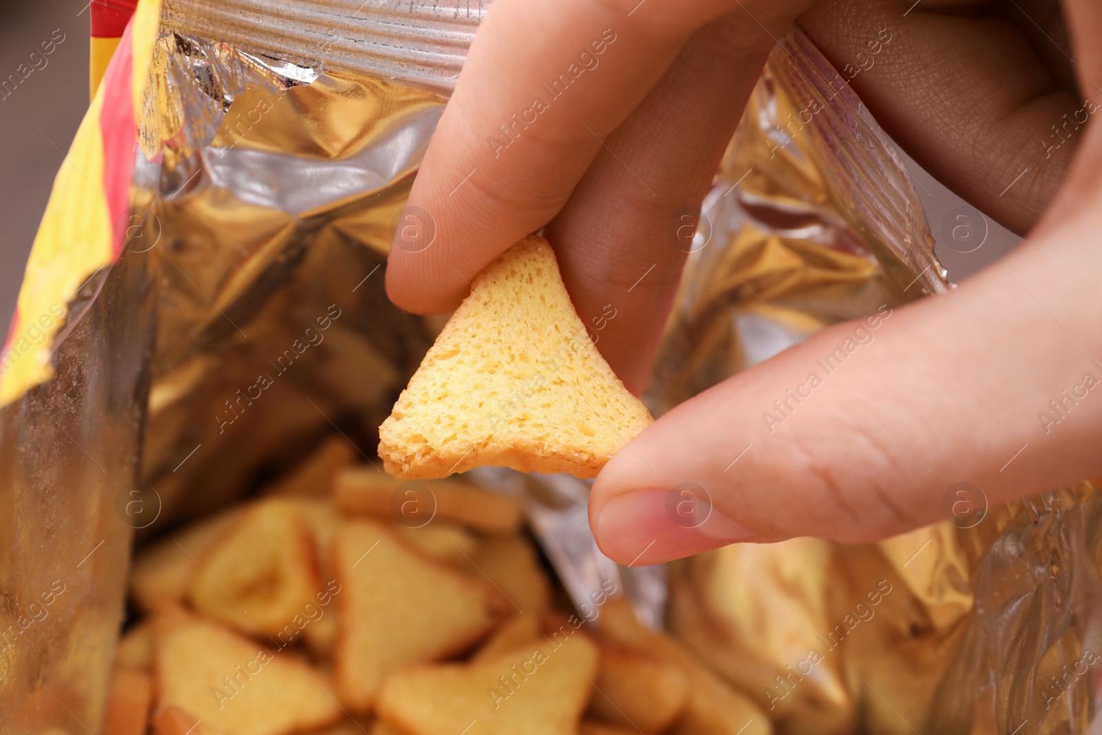 Photo of Woman taking crispy rusk out of package, closeup