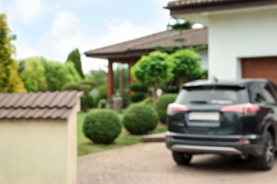 Photo of Beautiful house, green garden and parked car, blurred view