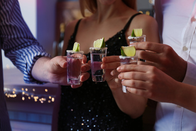 Photo of Young people toasting with Mexican Tequila shots in bar, closeup