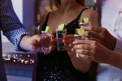 Young people toasting with Mexican Tequila shots in bar, closeup