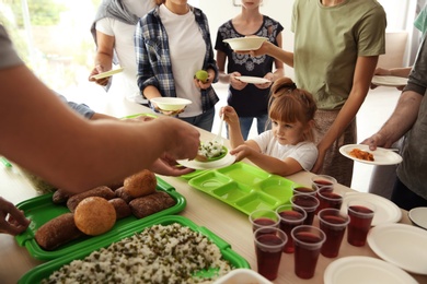 Volunteers serving food for poor people indoors