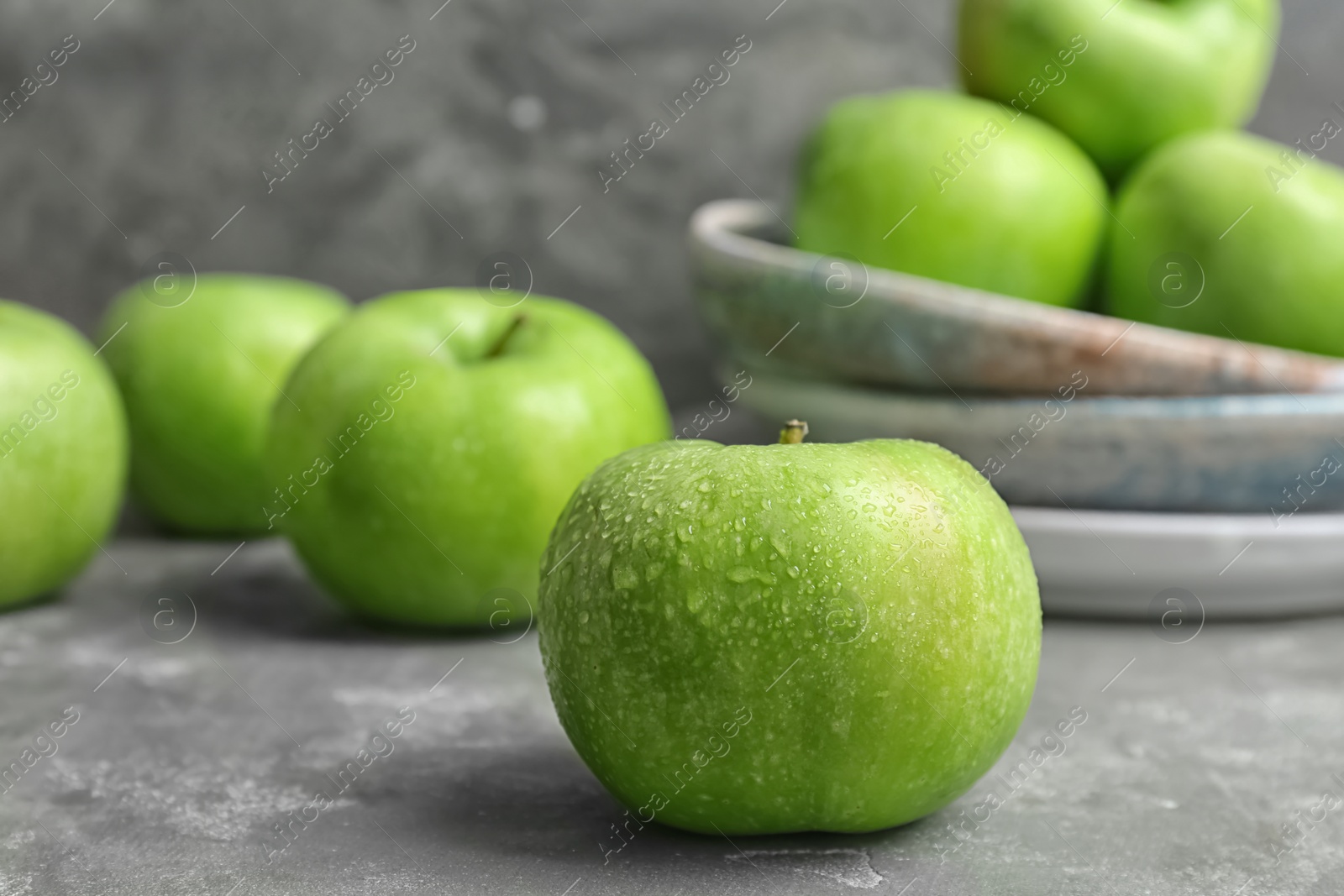 Photo of Fresh green apple with water drops on grey table