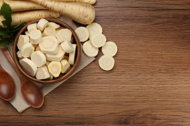 Flat lay composition with whole and cut fresh ripe parsnips on wooden table. Space for text
