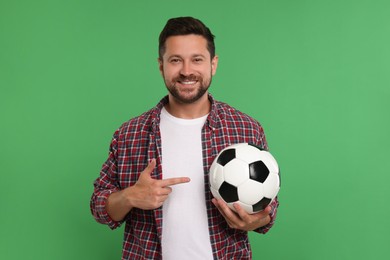 Photo of Happy sports fan with ball on green background