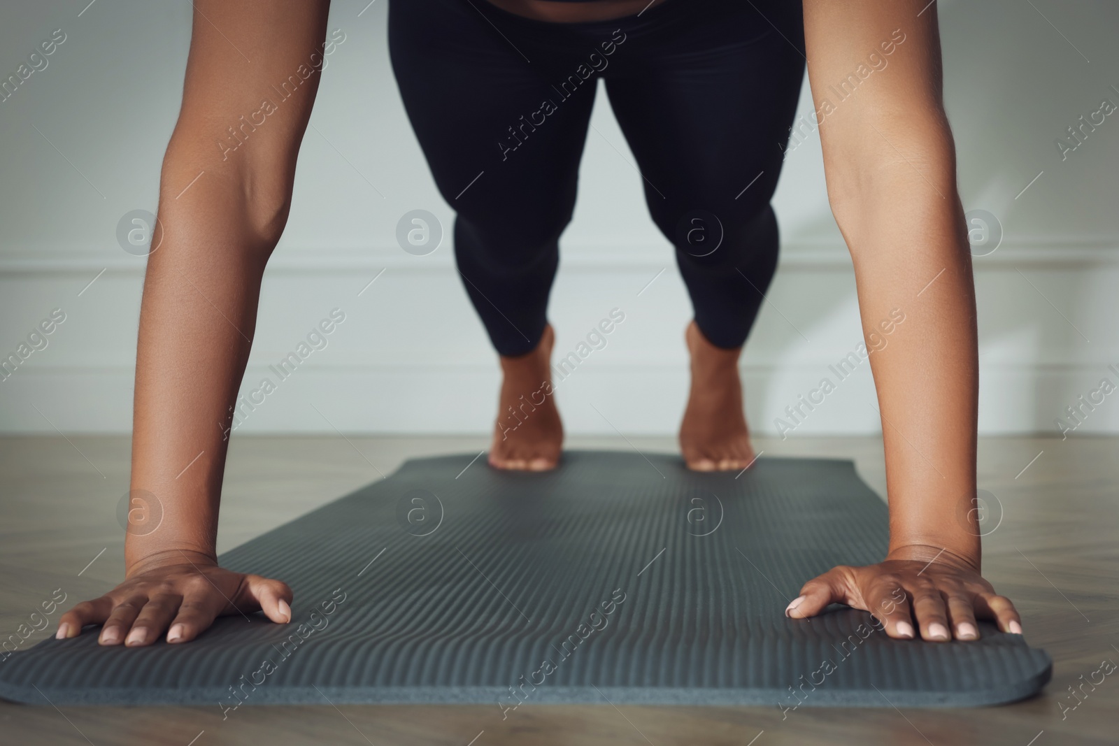 Photo of Young woman doing plank exercise indoors, closeup