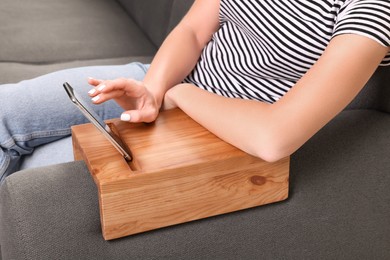 Photo of Woman using smartphone on sofa armrest wooden table at home, closeup