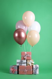 Photo of Bunch of color balloons and beautifully wrapped gift boxes on green background